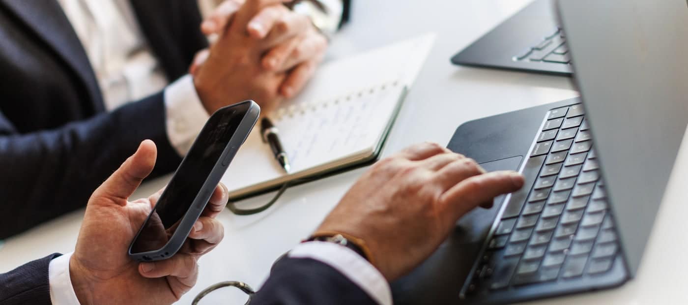 Deux conseillers en gestion de patrimoine travaillant avec un smartphone et un ordinateur portable
